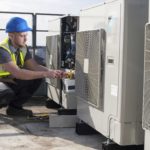 Technician working on an HVAC system on the rooftop of a building.