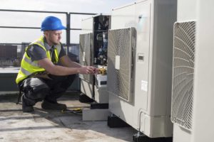 Technician working on an HVAC system on the rooftop of a building.