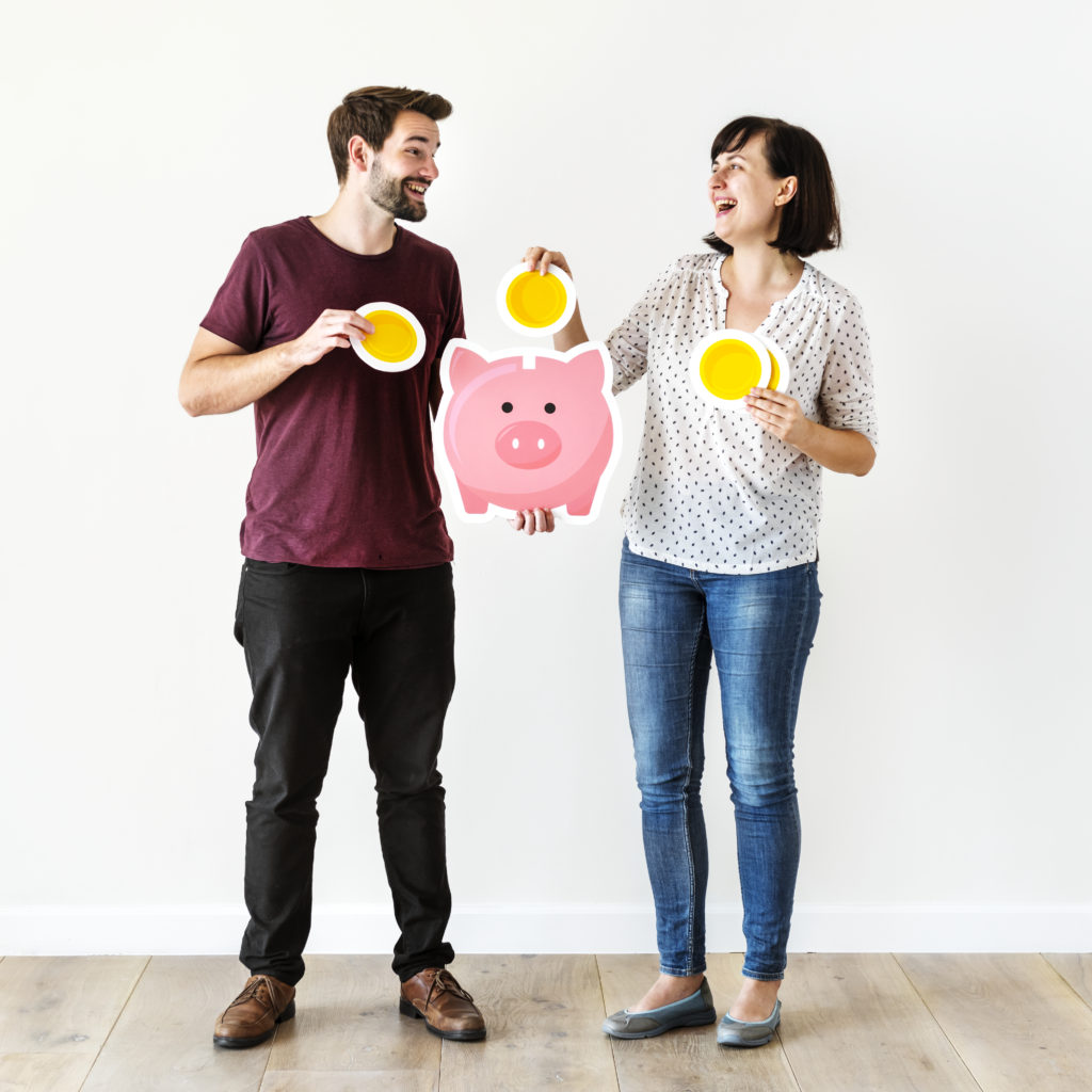 Man and woman enjoying saving. Paper Piggy bank and coins.
