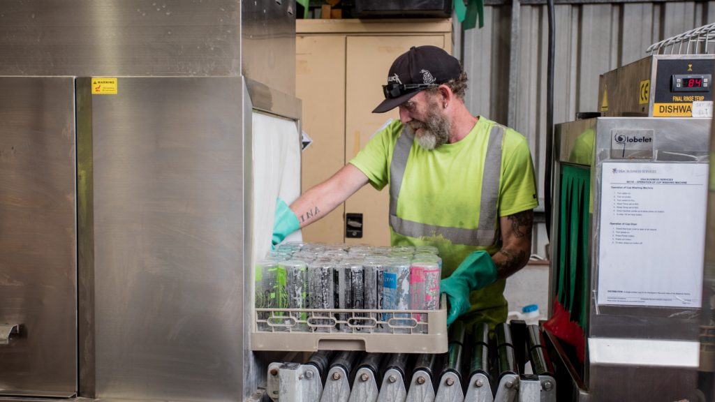 Commercial dishwasher being worked on by technician. 